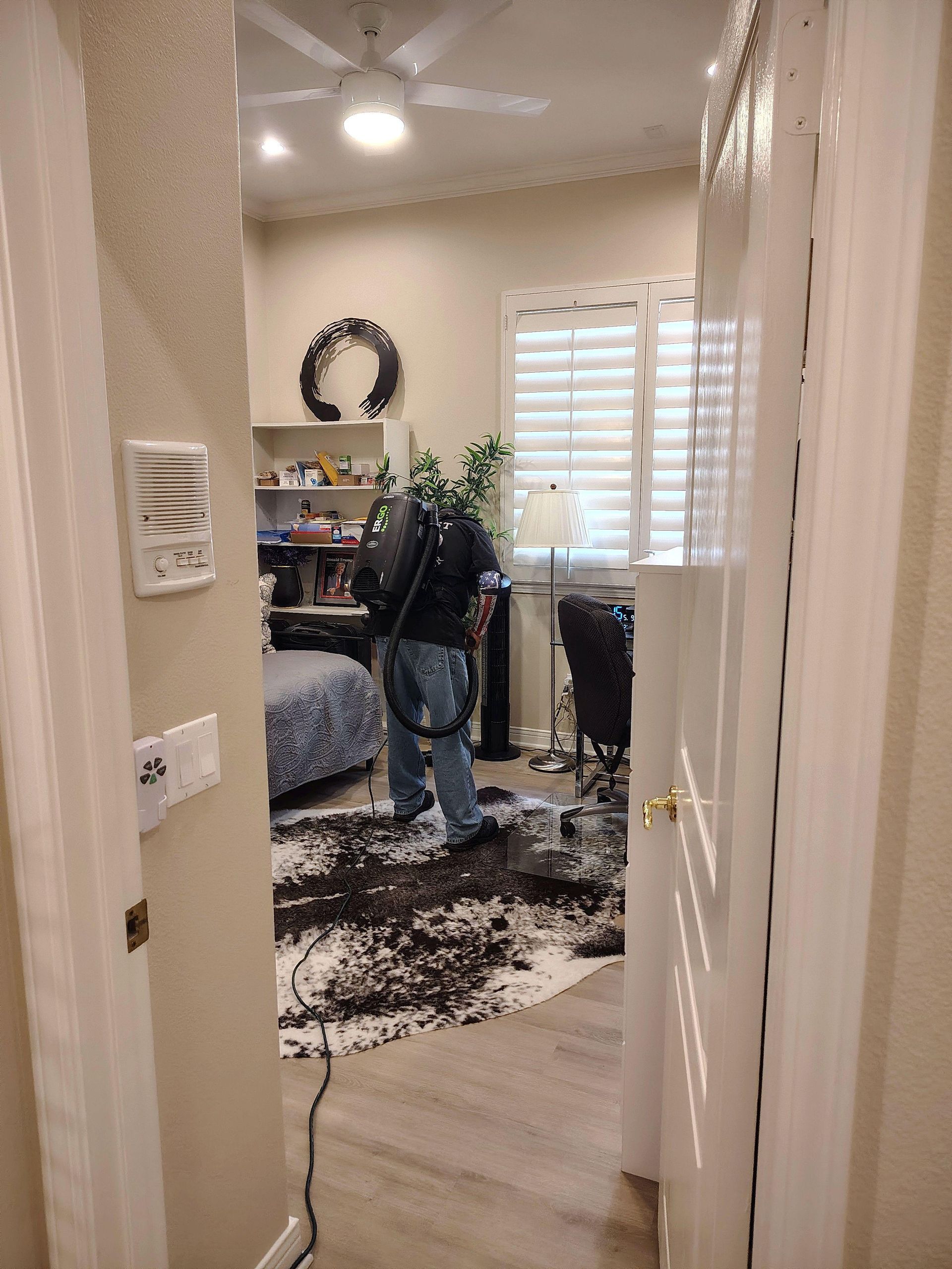 Open doorway to a cozy bedroom with a bed, plants, window blinds, and a shag rug.