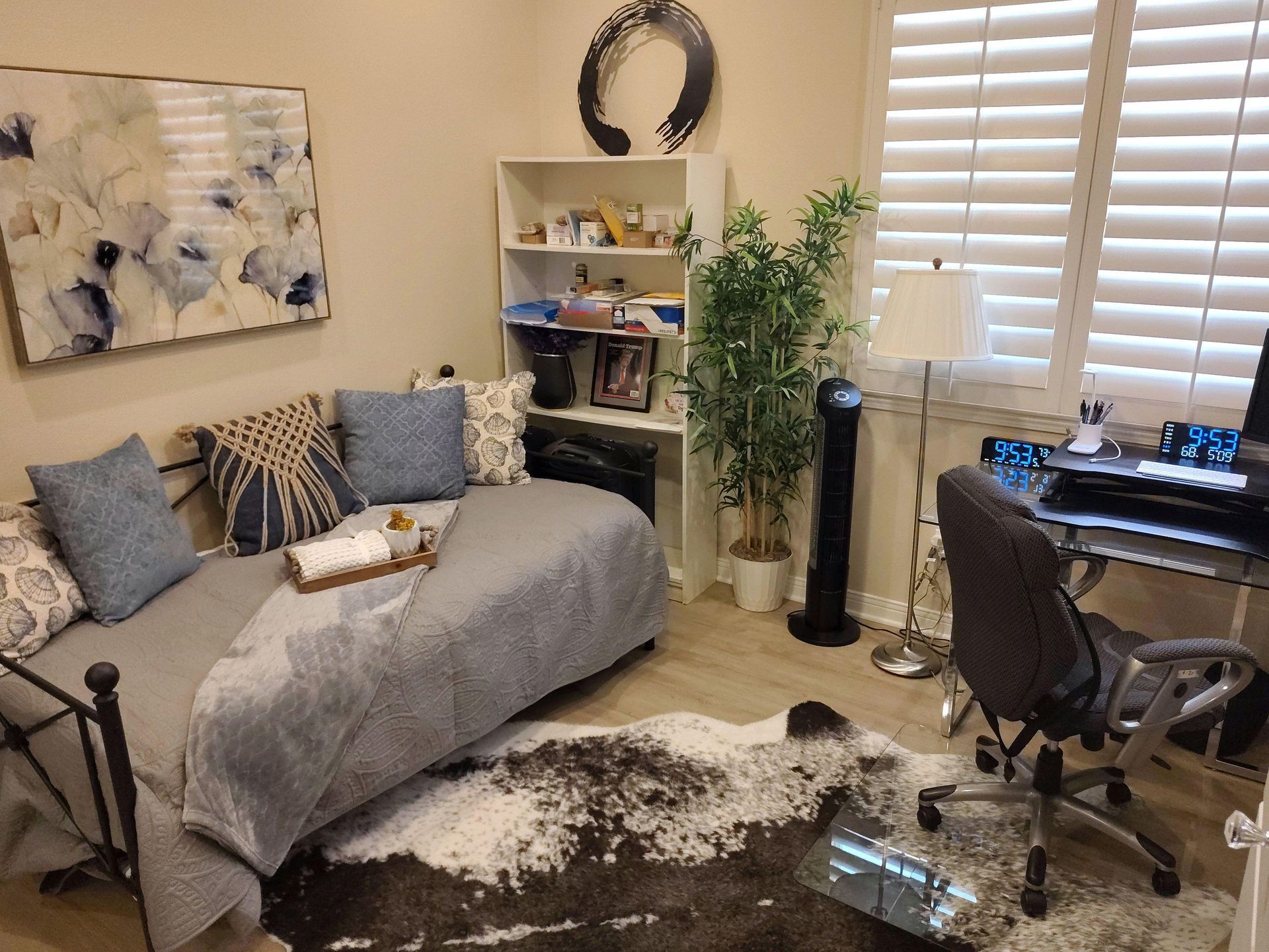 Cozy home office with gray chaise, desk, chair, shelves, plant, and window blinds