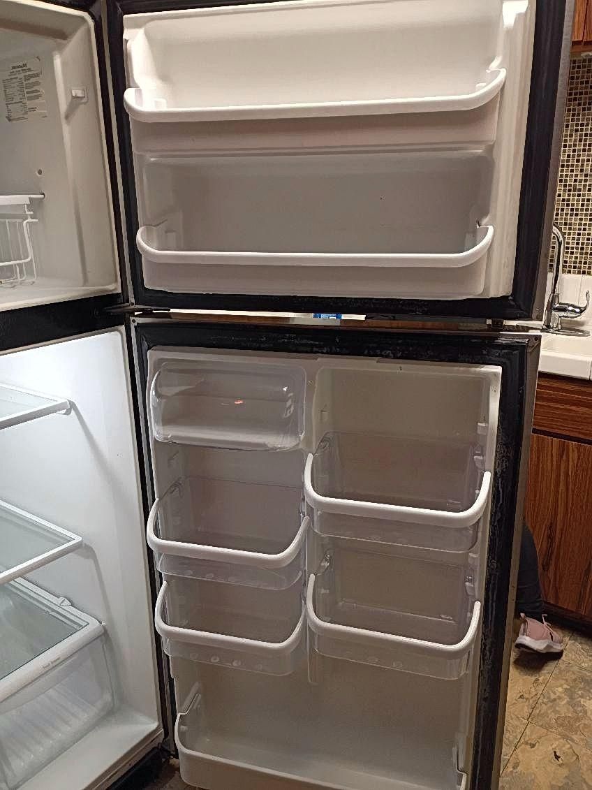 Open refrigerator with empty clear storage bins on the door and shelves