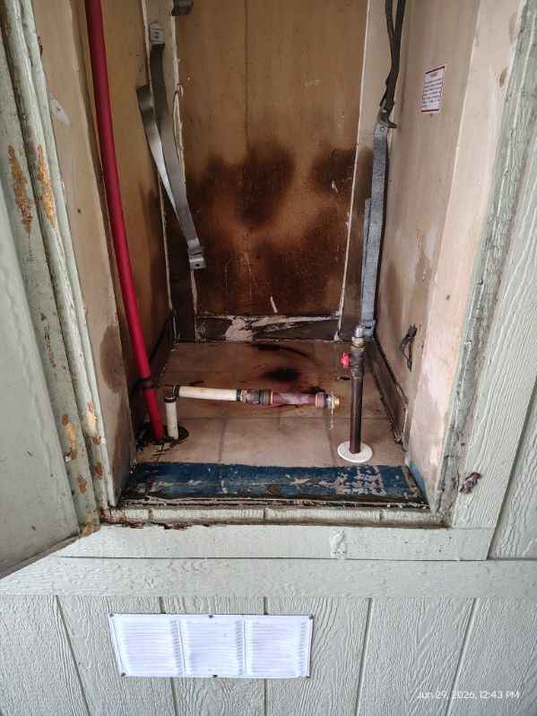Burned-out front door with charred wood and damaged threshold in a narrow entryway