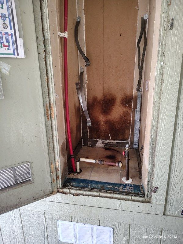 Open electrical panel with exposed wires and burn marks in a wall recess