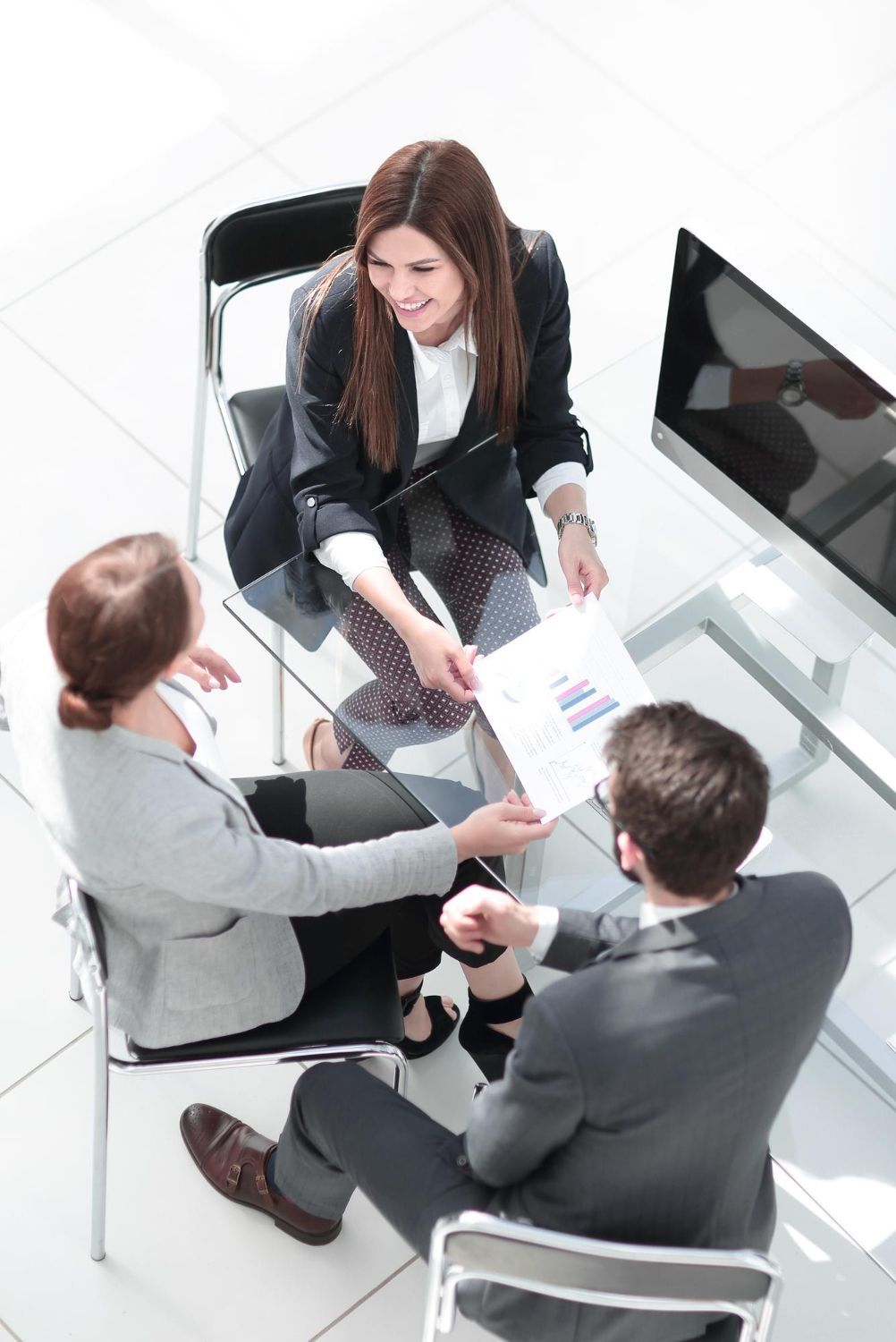 Three people reviewing paperwork at a table in an office setting.