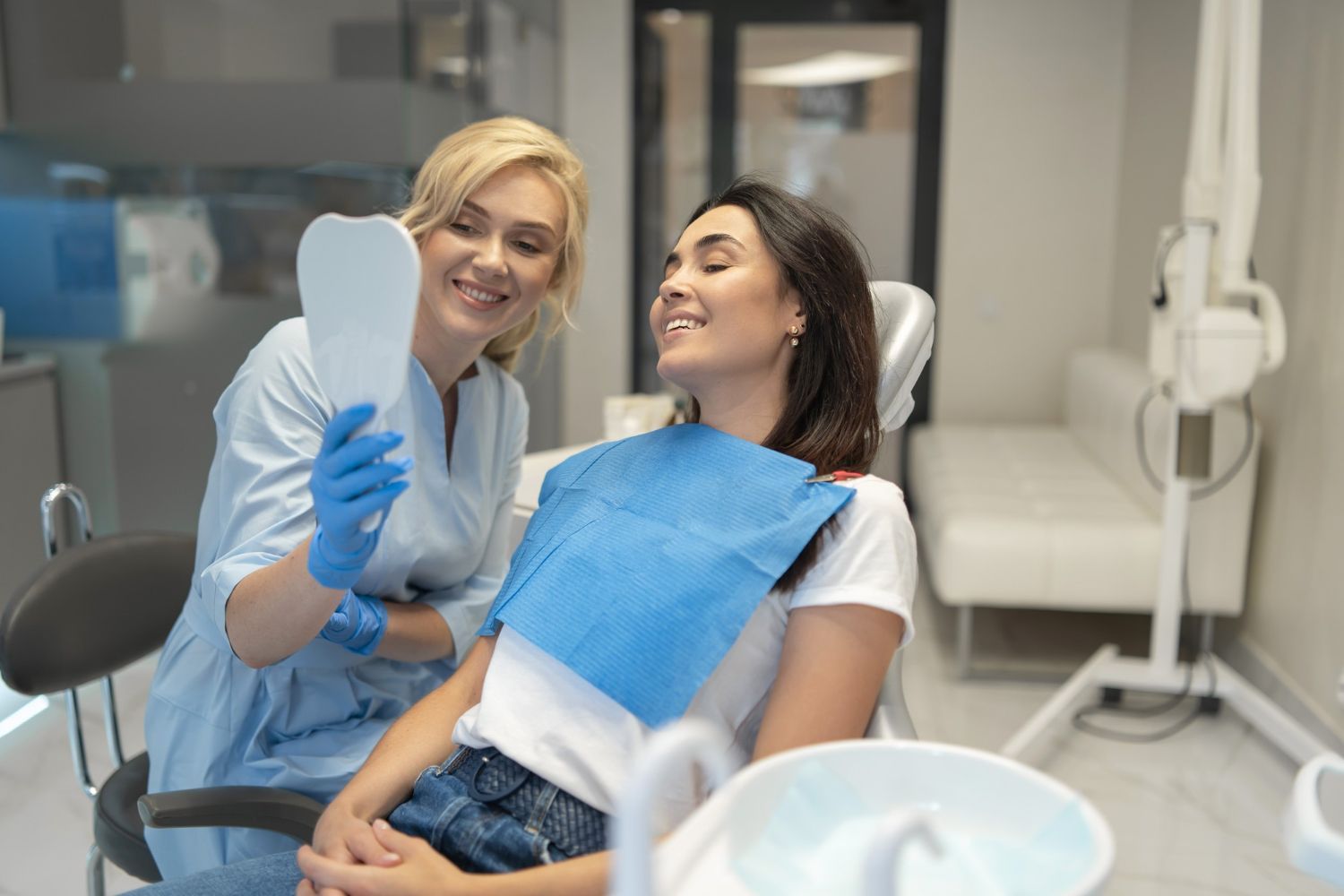 Dentist showing a patient their teeth in a mirror at a dental office.