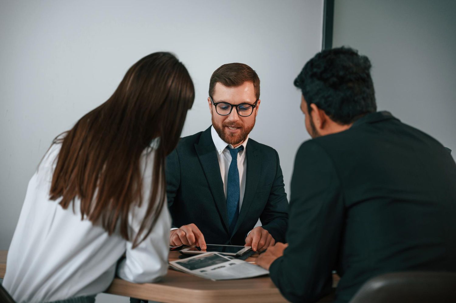 Three people, two in business attire, reviewing documents at a table.