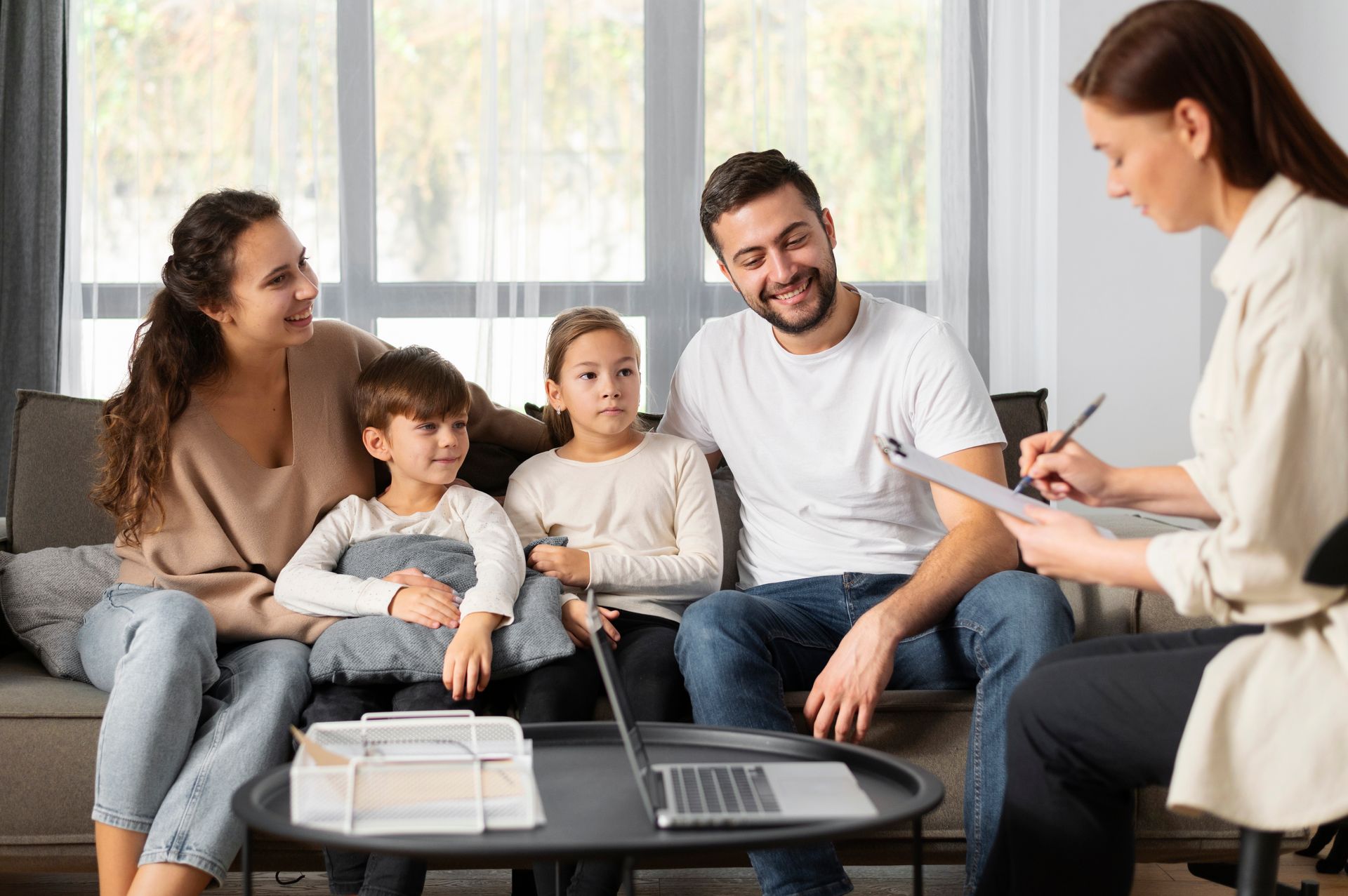 Family consulting with a professional, sitting on a couch in a home setting.