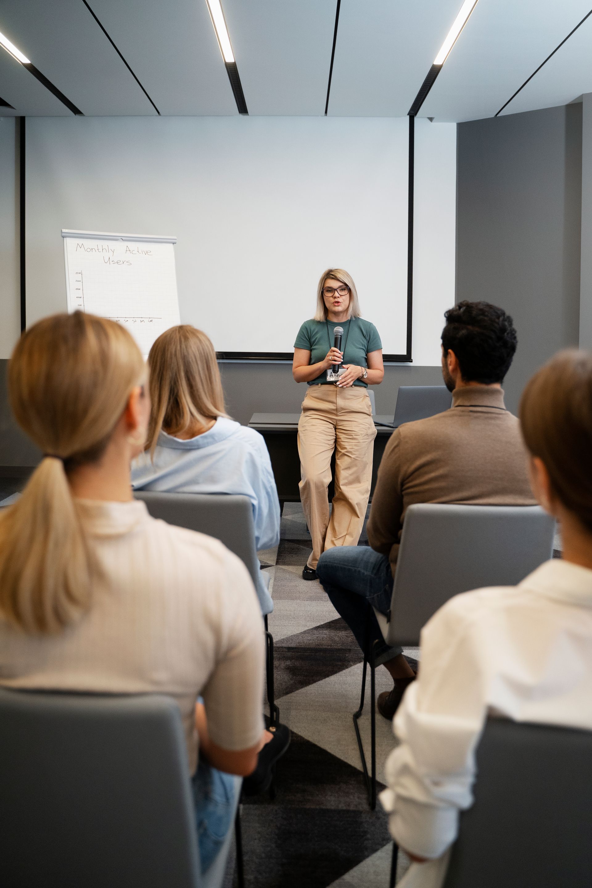 Woman speaking at a presentation in front of a small audience.