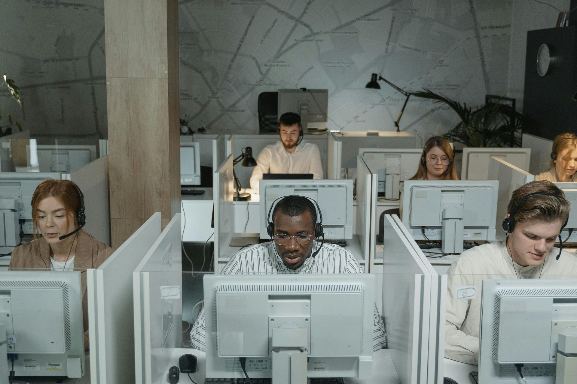 People in an office wearing headsets, working at computers in cubicles.