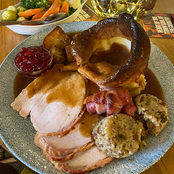 Plate of roast turkey with Yorkshire pudding, stuffing, gravy, and cranberry sauce.