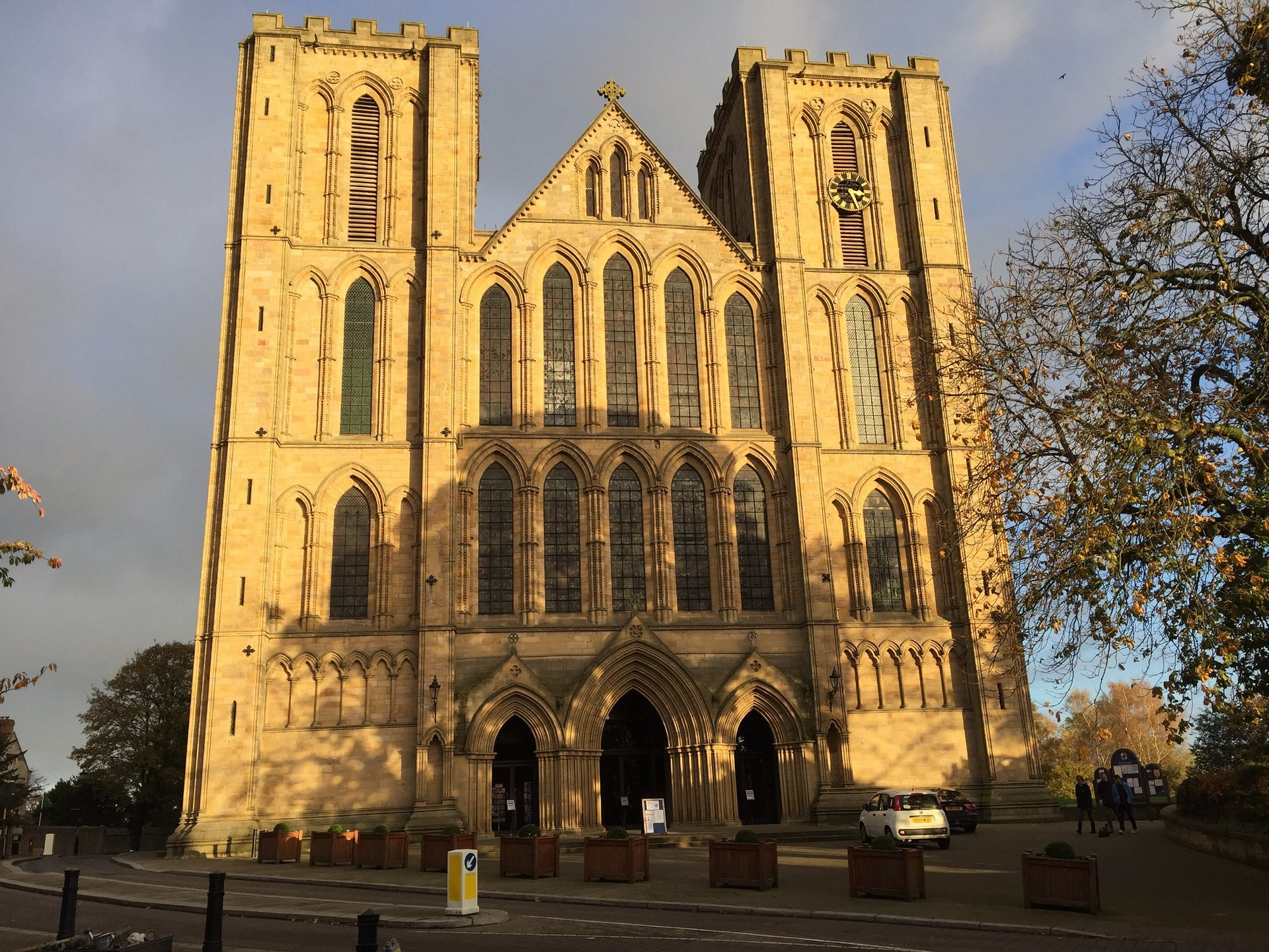 Large stone cathedral with twin towers, arched windows, and entrance; sunny day.