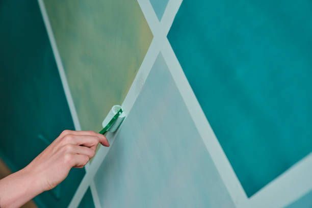A person is using a toothbrush to paint a wall.