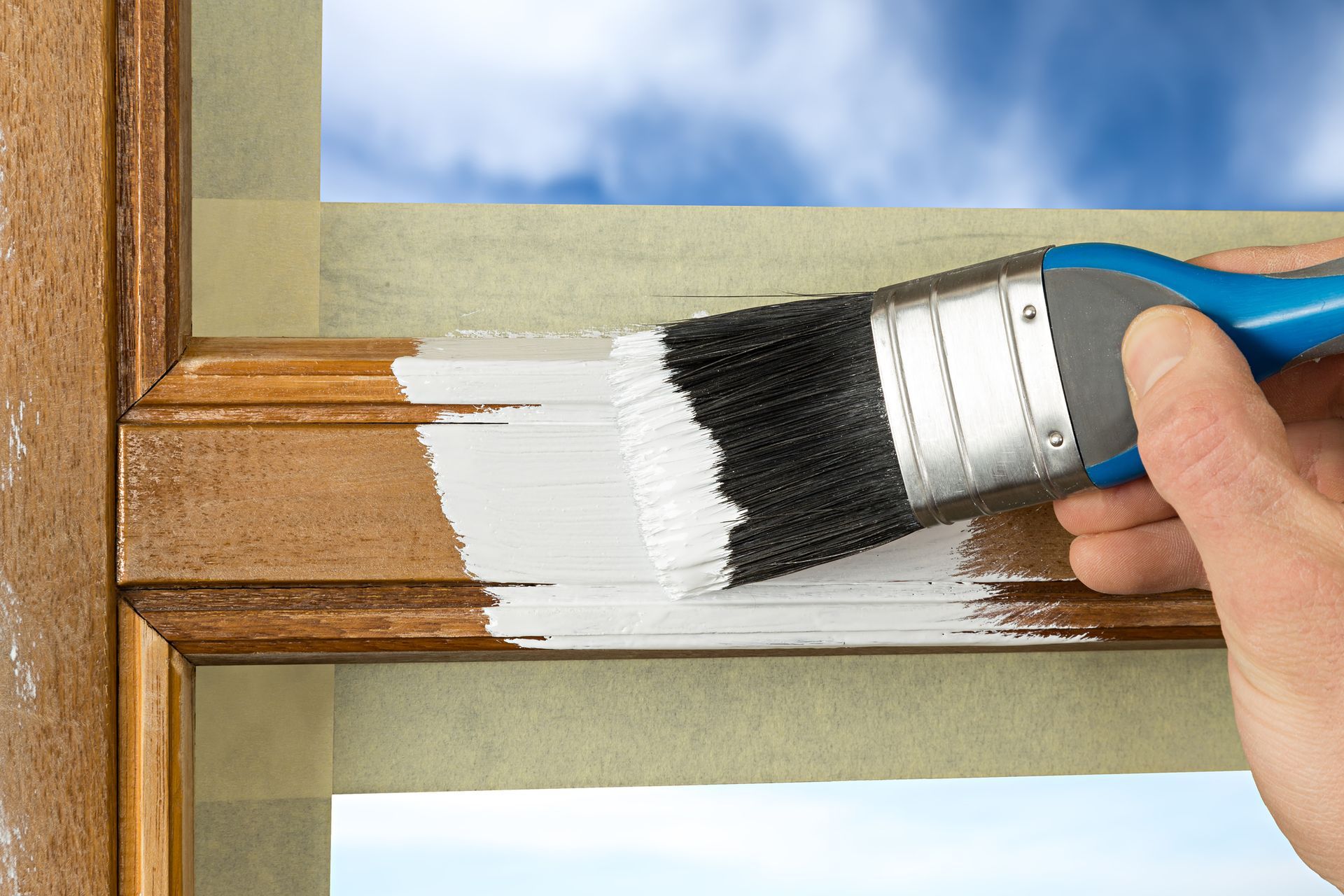 A person is painting a window frame with a brush