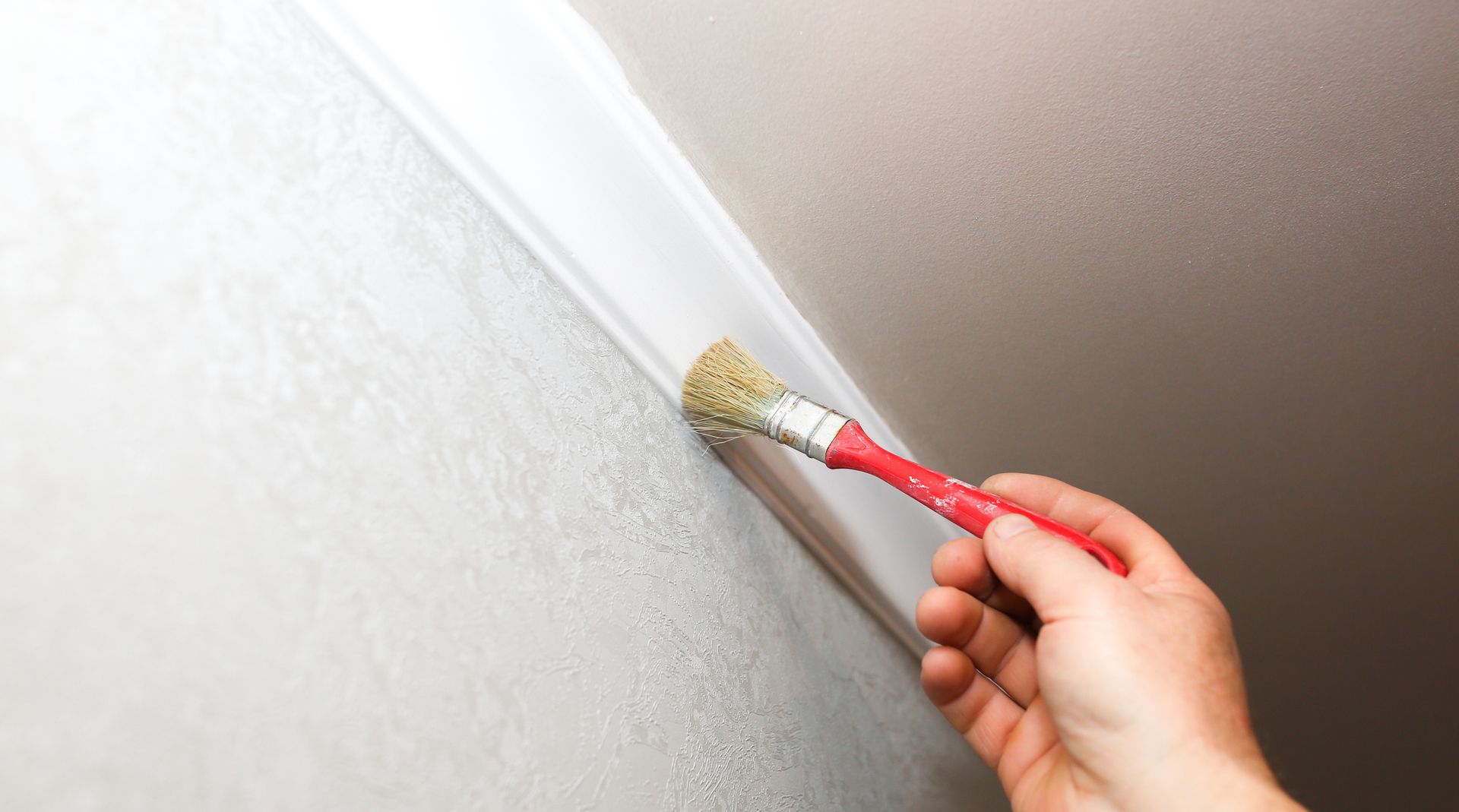 A person is painting a wall with a brush.