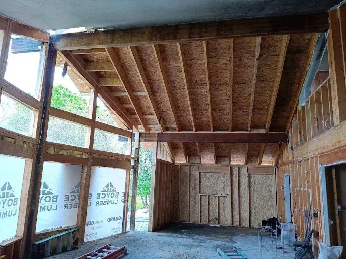 Interior framing of a building under construction; exposed wooden beams, walls, and OSB sheathing.