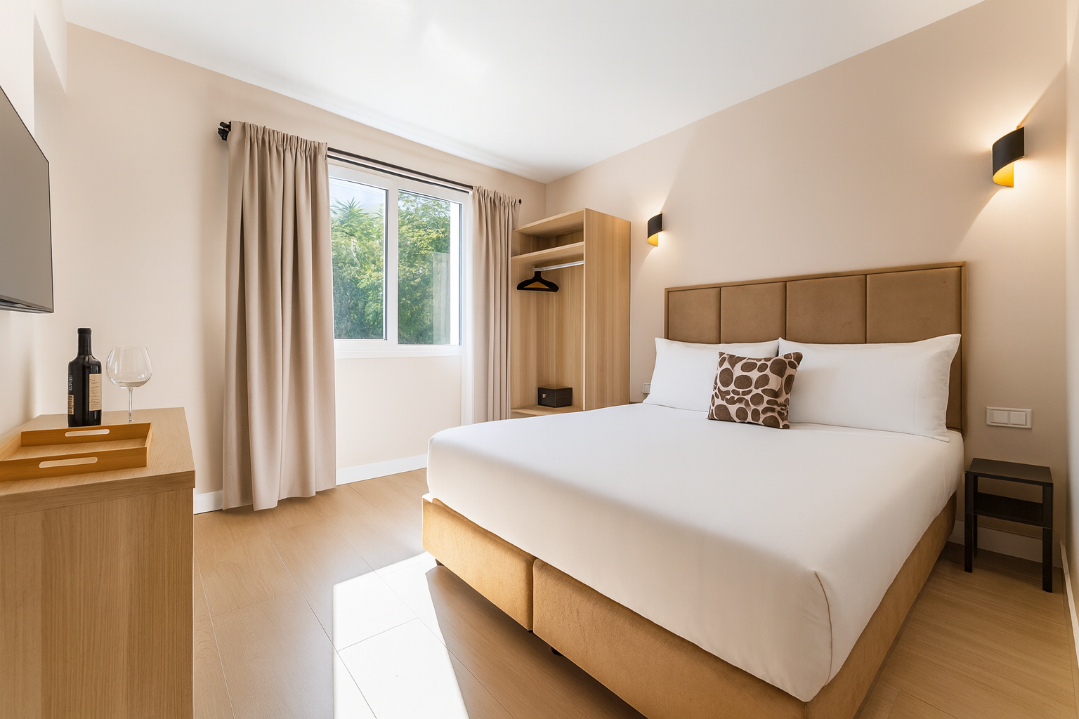 Dormitorio con cama grande, muebles de madera clara, ventana y paredes color beige.