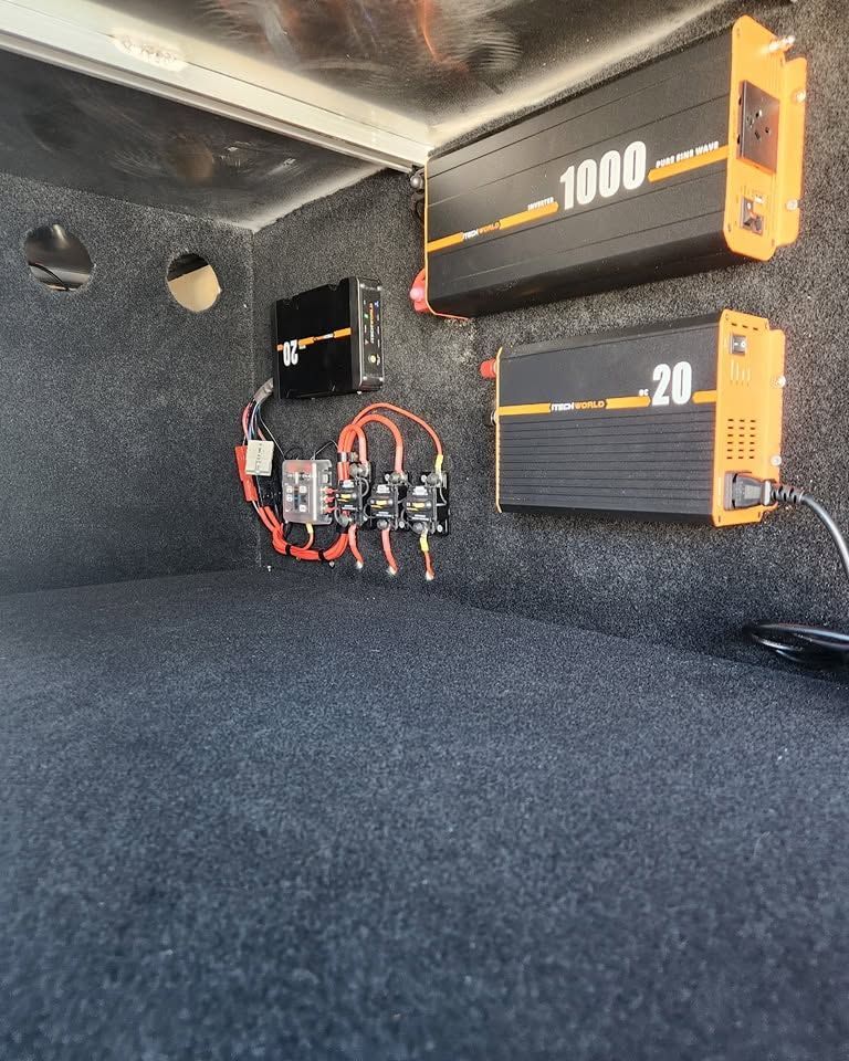 Car trunk with two orange-and-black power inverters and wiring mounted on the side wall — Smart Automotive Technologies in Noosaville, QLD