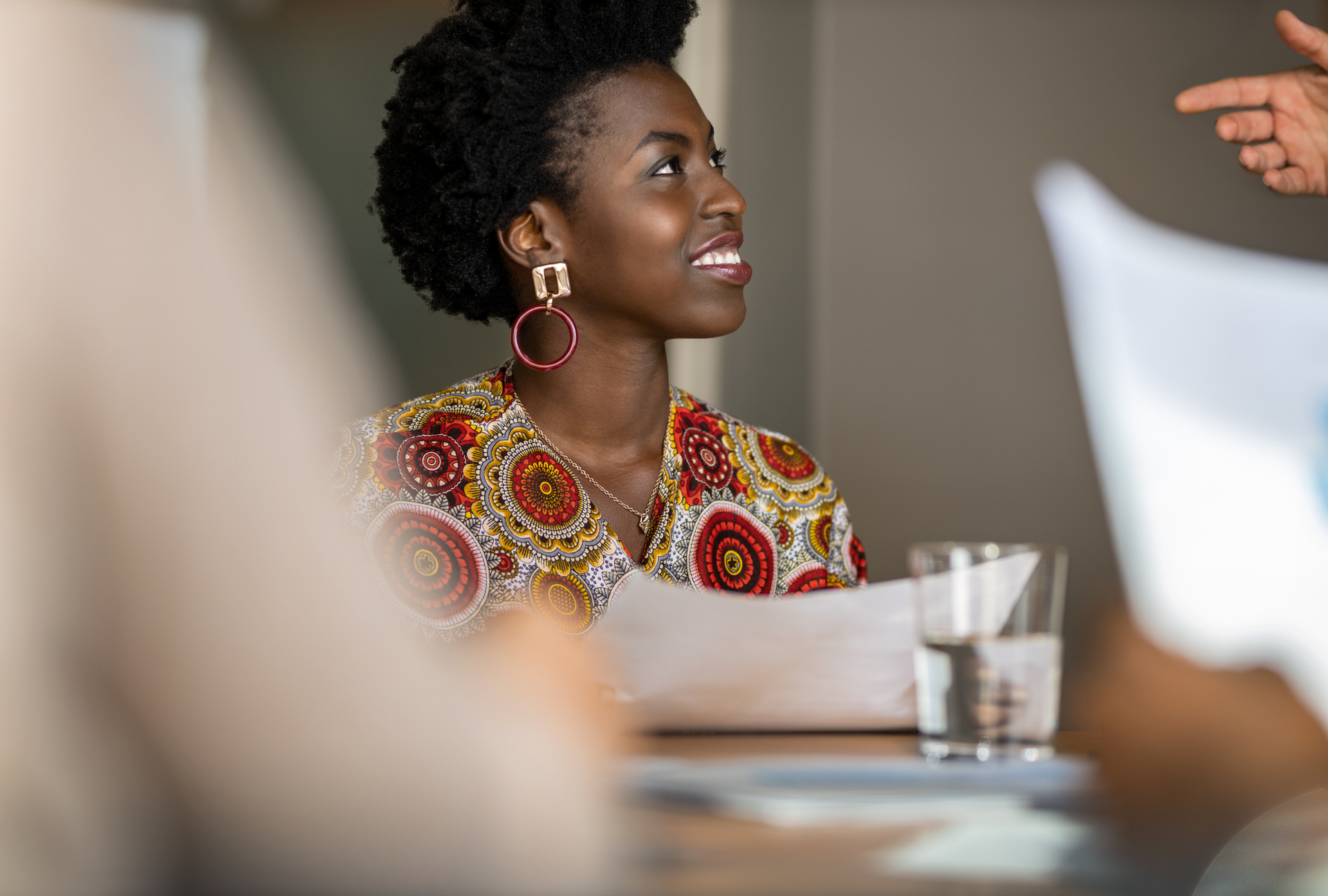 A woman is sitting at a desk holding a cell phone and a notebook.
