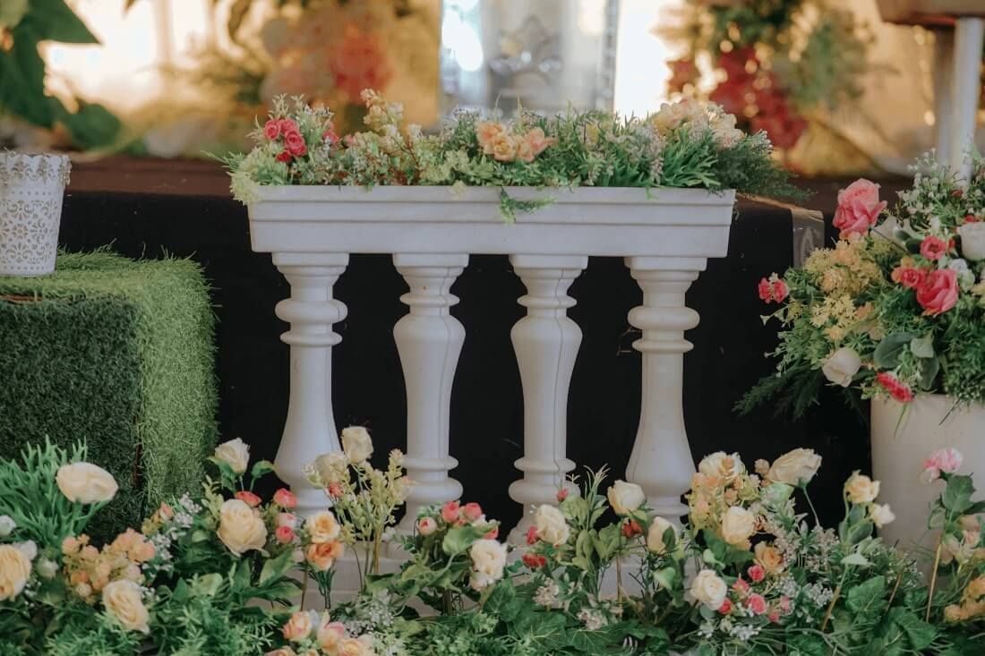 A white decorative stand surrounded by lush pastel flowers creates a serene memorial display with cremation services in New Orleans, LA