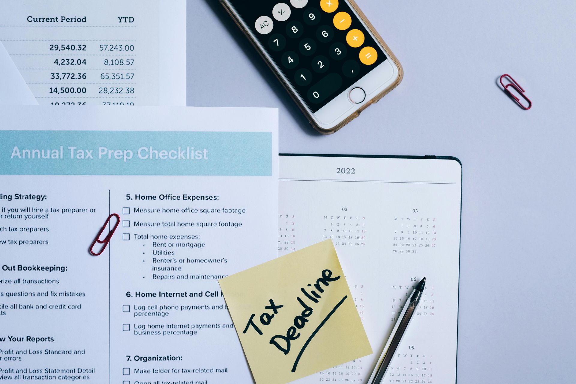 Tax preparation items on a desk: checklist, calculator, calendar, pen, and note reading 