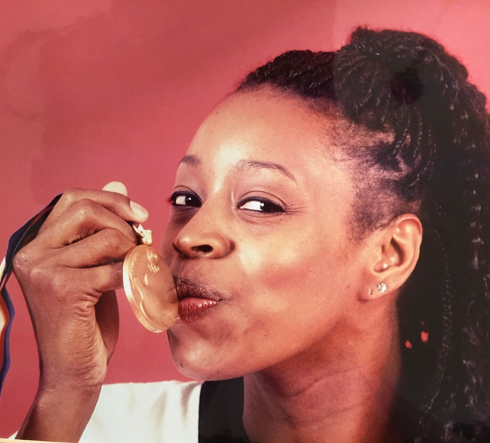 A close up of a woman holding a medal in her mouth