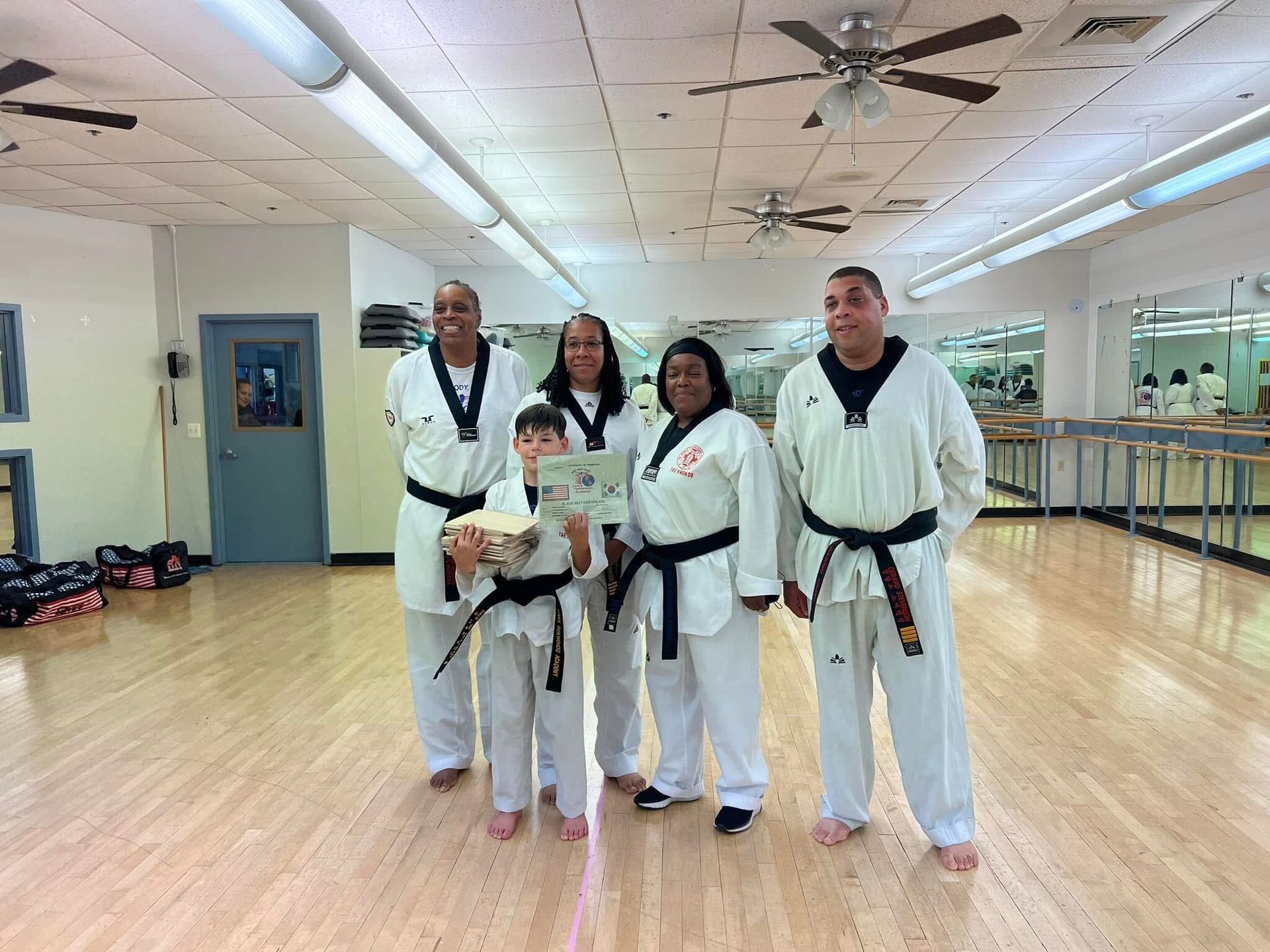 A group of people in karate uniforms are posing for a picture in a gym.