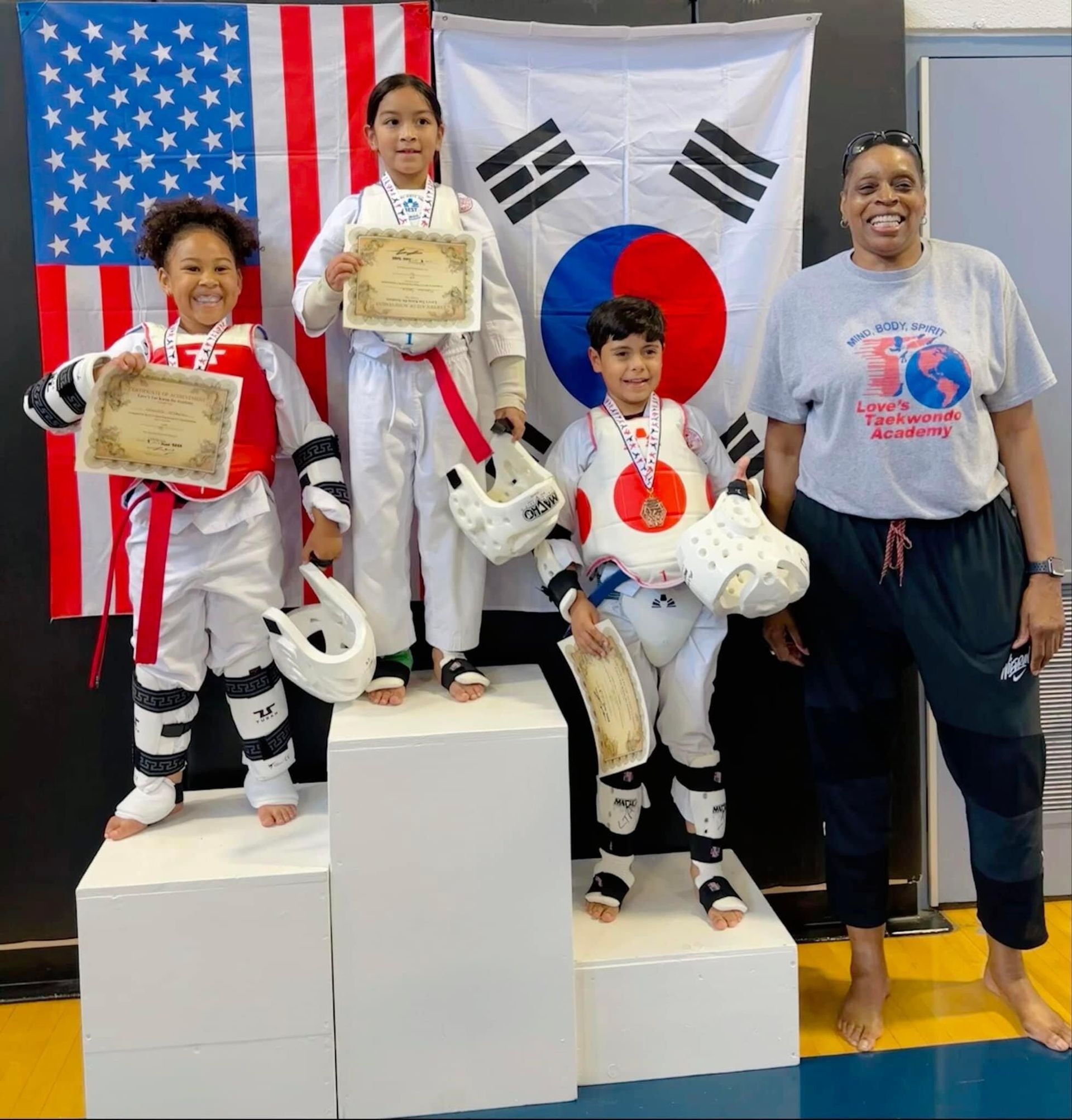 A group of kids standing on a podium in front of a flag