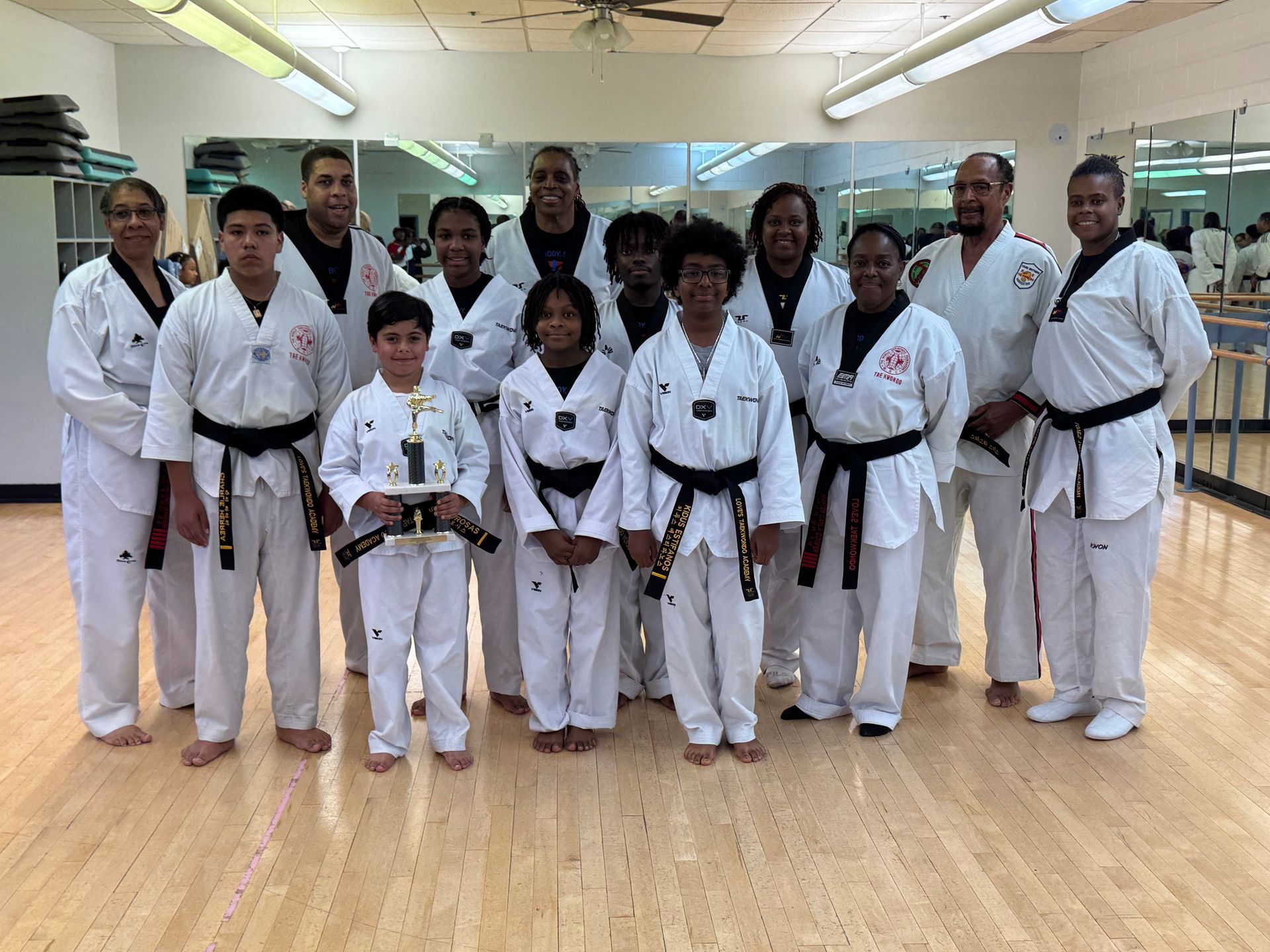 A group of people in karate uniforms are posing for a picture in a gym.