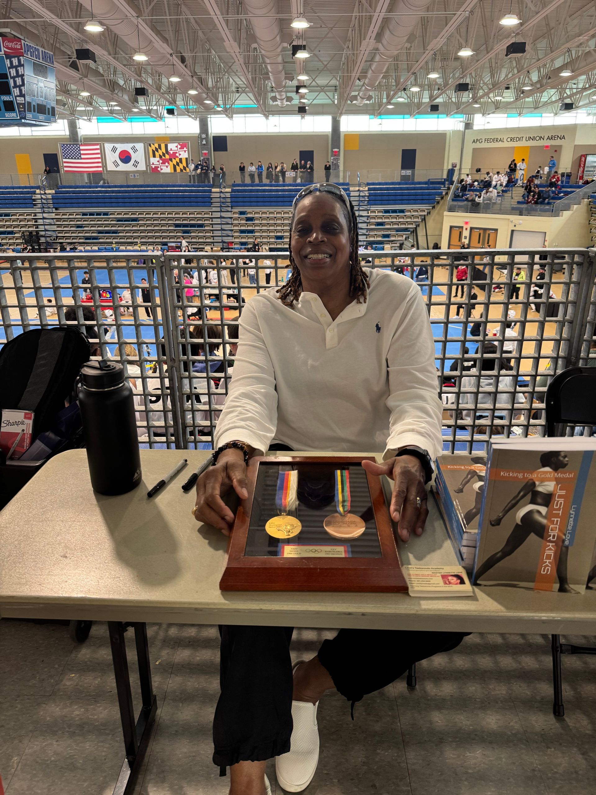A woman is sitting at a table holding a medal