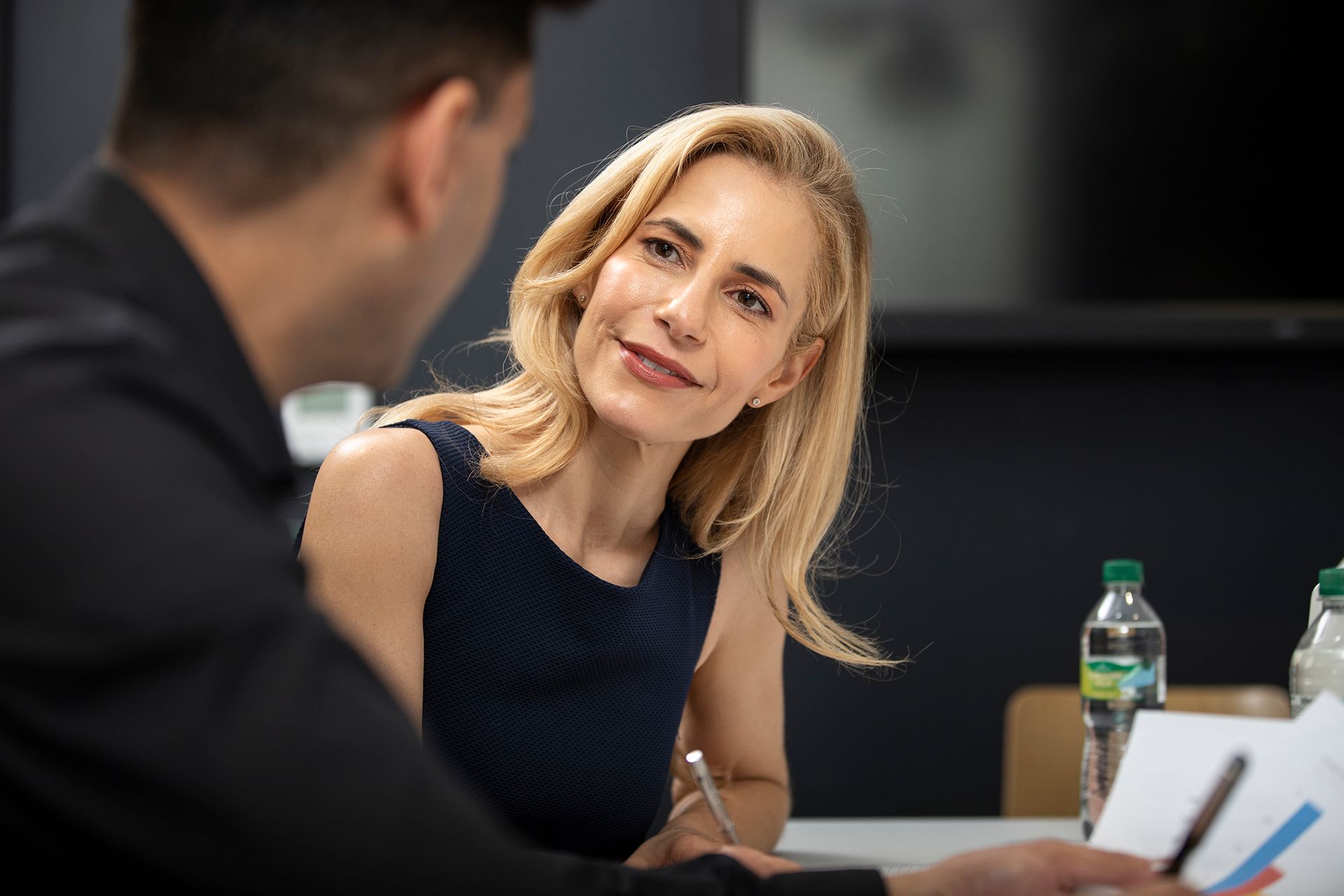 A man and a woman are sitting at a table talking to each other.