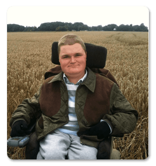 A man in a wheelchair is sitting in a field of wheat