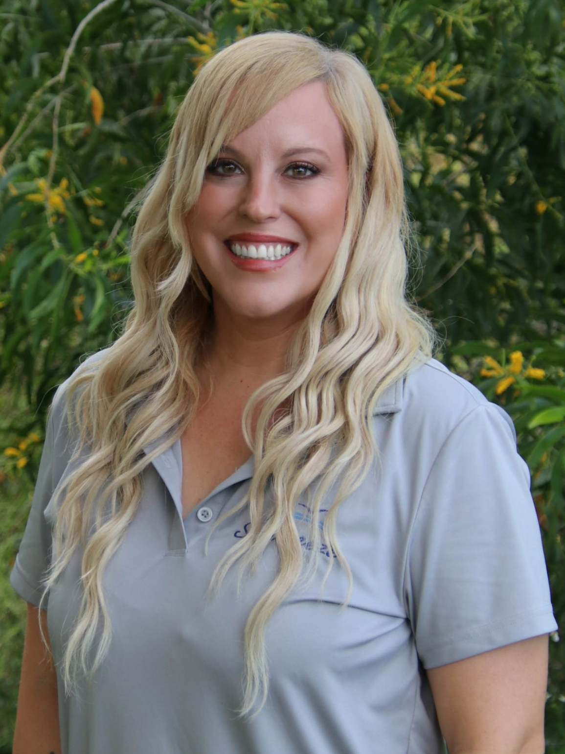 Woman with blonde hair in a white polo shirt with
