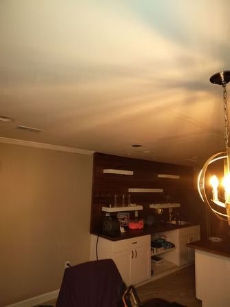 A dimly lit kitchen area with white cabinets.