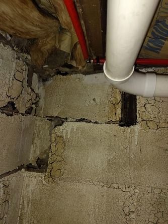 A horizontal crack runs along a cinder block basement wall.