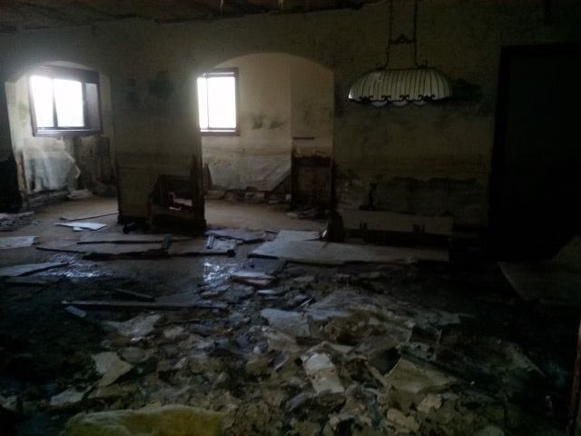 A dimly lit, dilapidated room filled with rubble and debris.