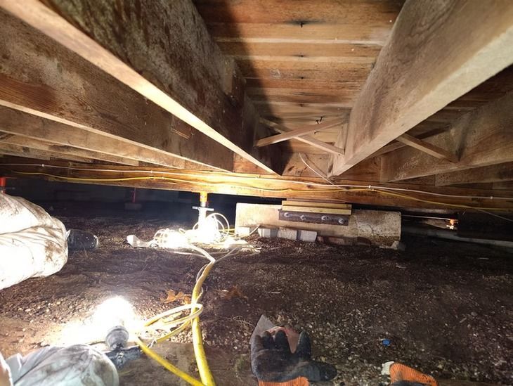 A crawl space beneath a wooden floor structure.