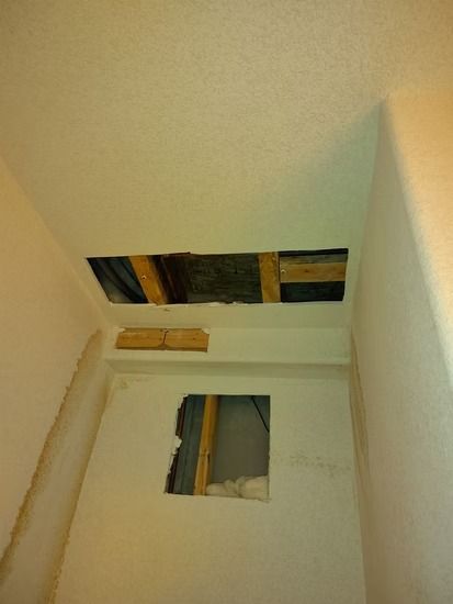 A view of a home interior showing holes cut into a ceiling and wall.