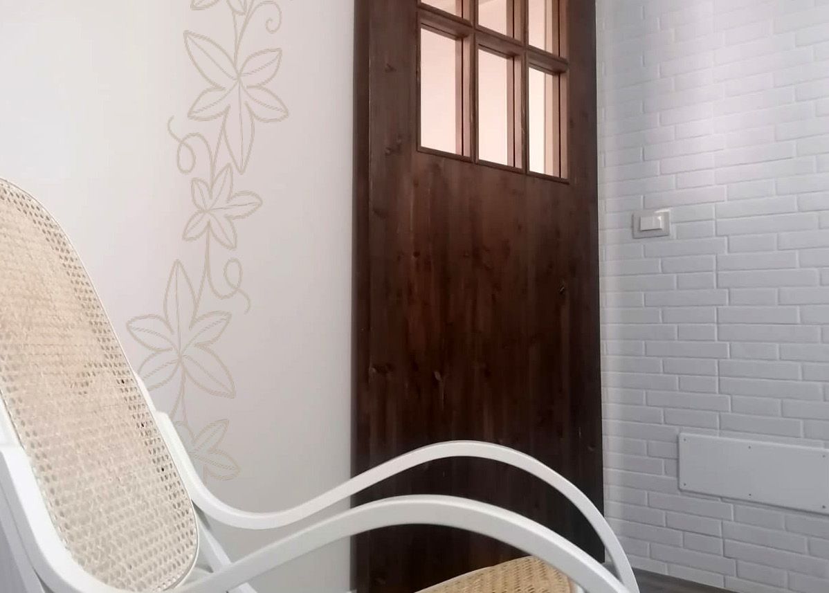 Una sedia a dondolo bianca davanti a una porta di legno