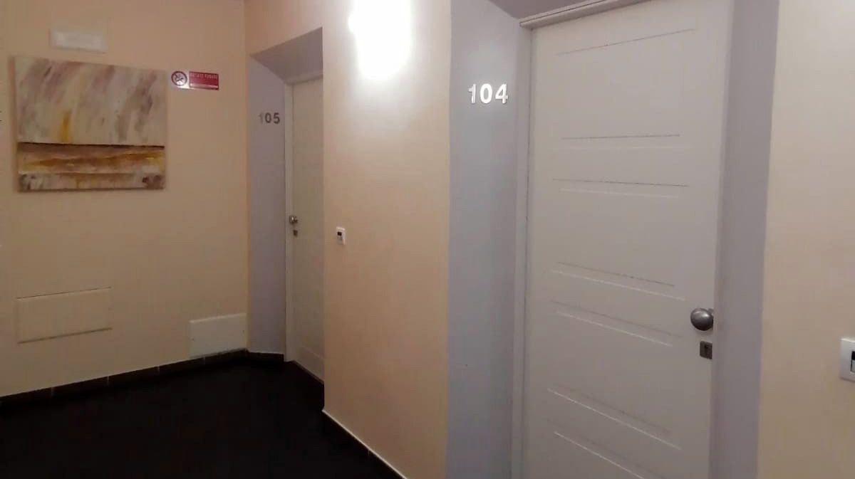 Un corridoio con una porta che riporta il numero 104.