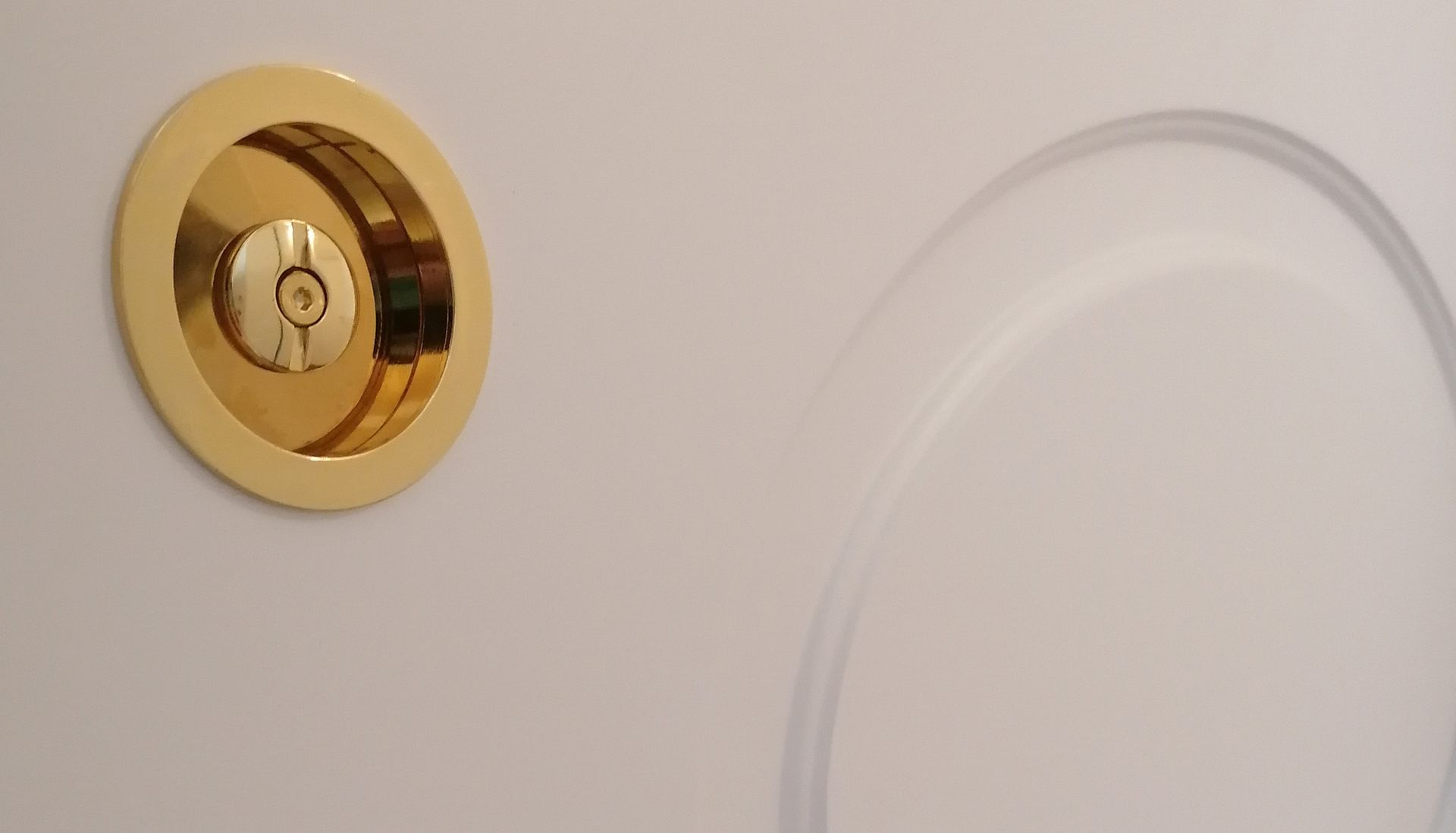 Un primo piano di una serratura dorata su una porta bianca