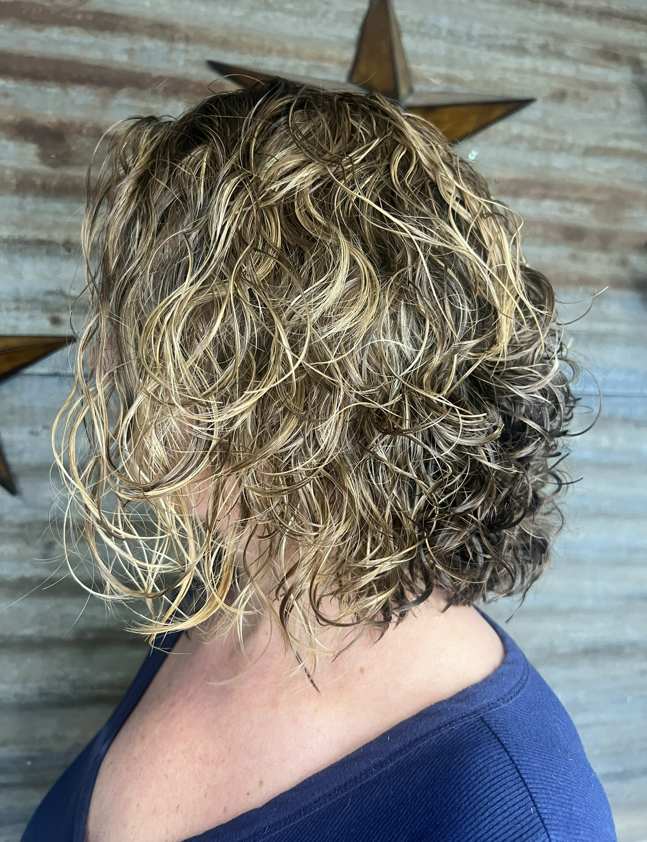 A woman with curly hair is wearing a blue shirt.