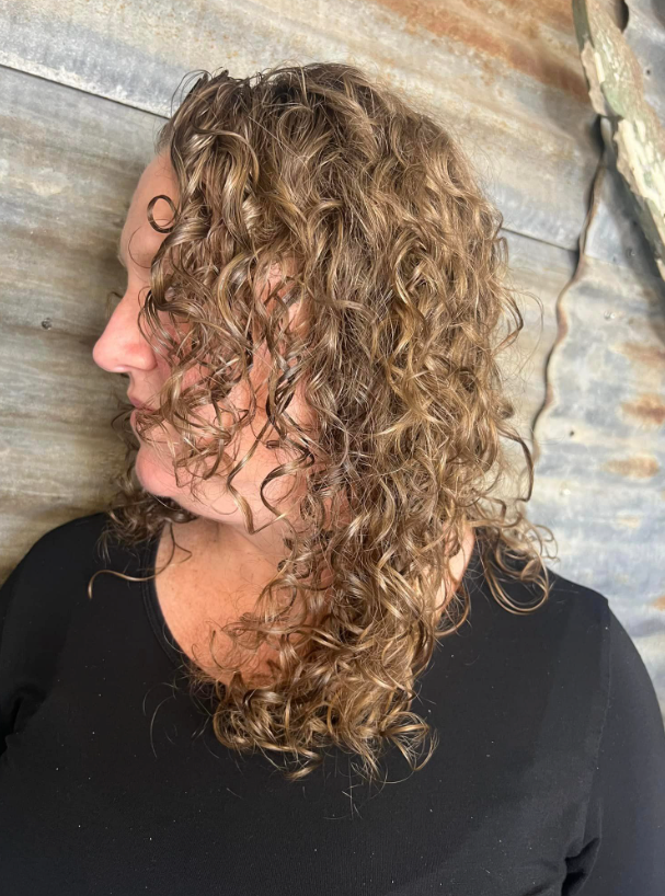 A woman with curly hair is wearing a black shirt.