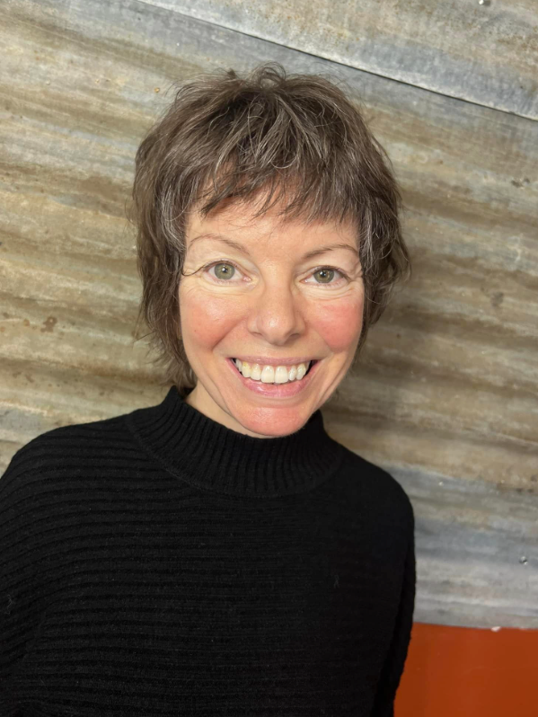 A woman in a black sweater is smiling for the camera.