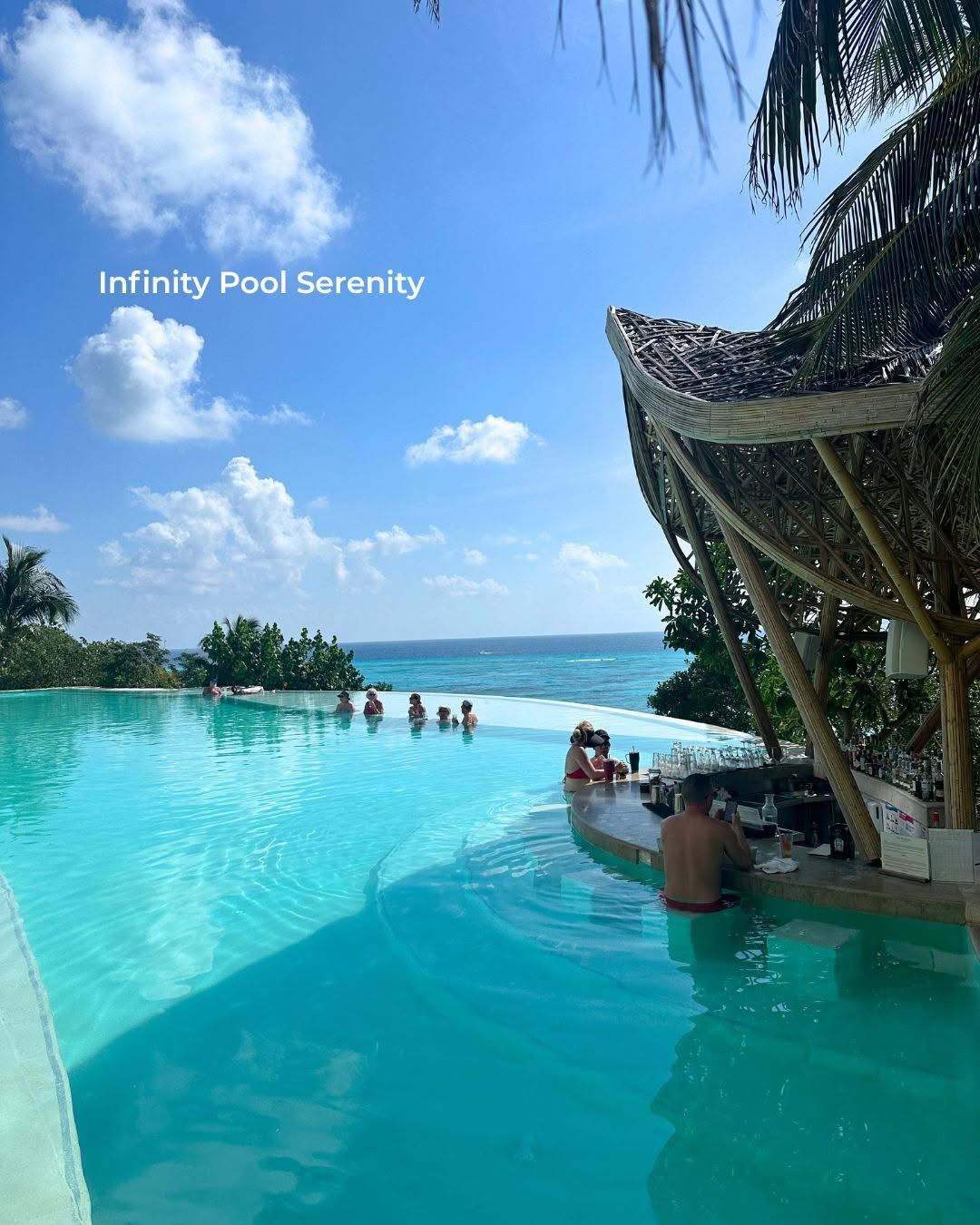 Infinity pool with turquoise water, people relaxing, and a bright tropical ocean view under a blue sky