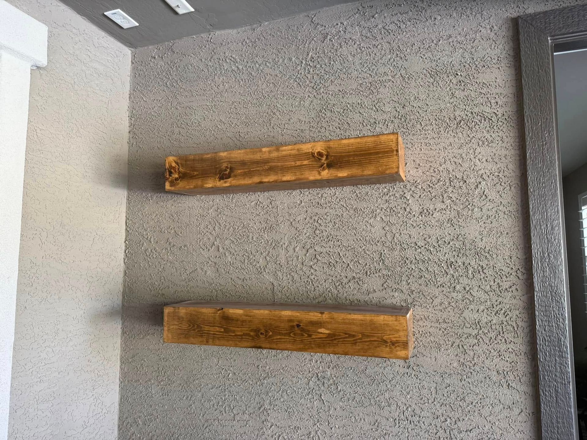 Two wooden shelves mounted on a textured gray wall.