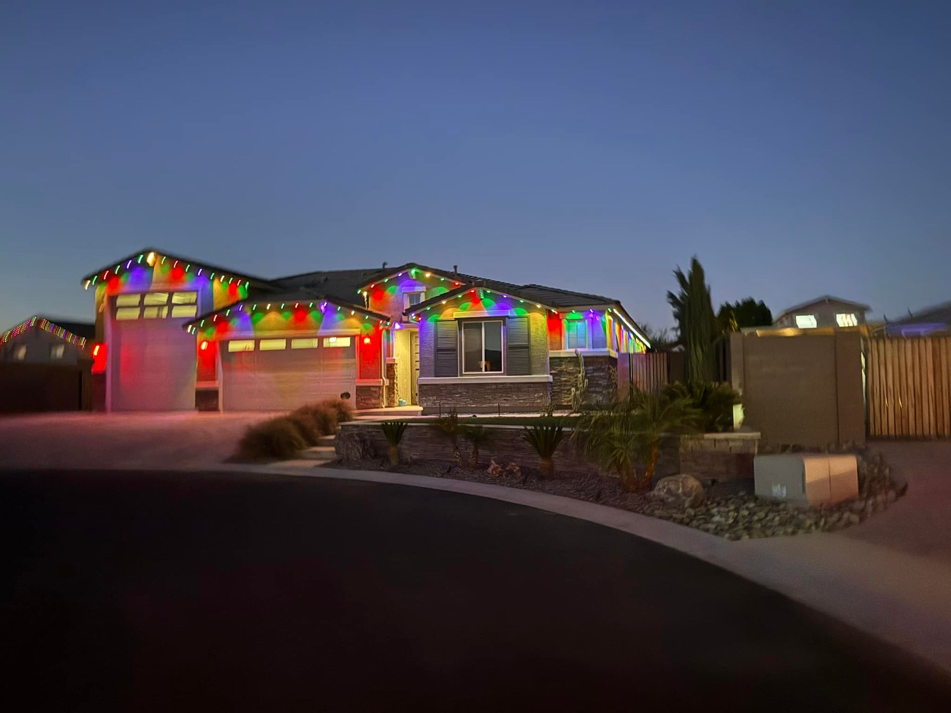 House decorated with colorful Christmas lights against a twilight sky.
