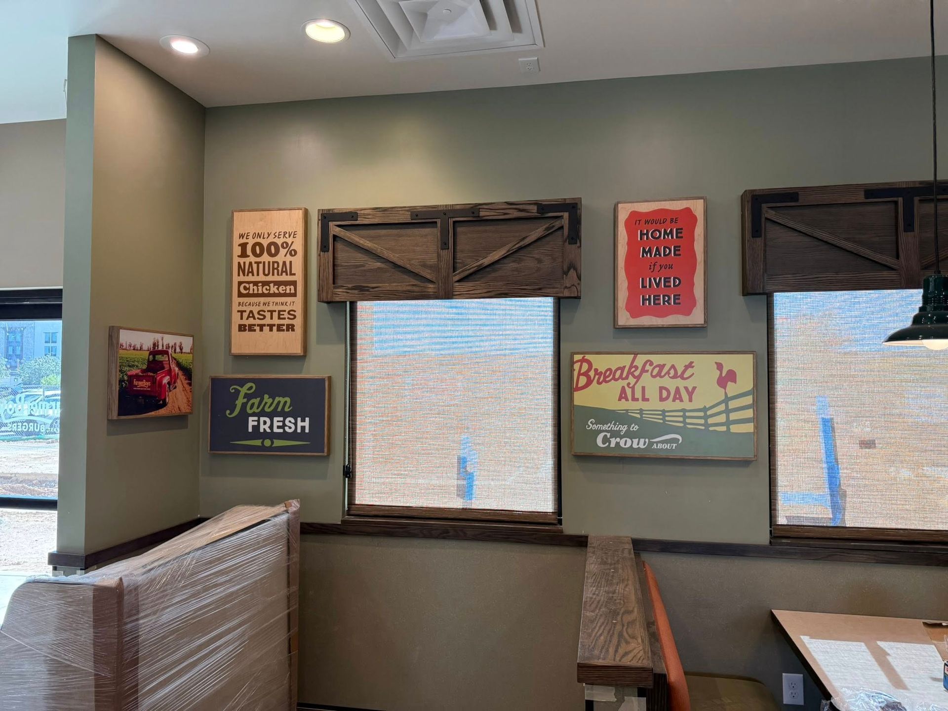 Interior wall with decorative signs. Farmhouse style dining area with wooden accents and olive green paint.