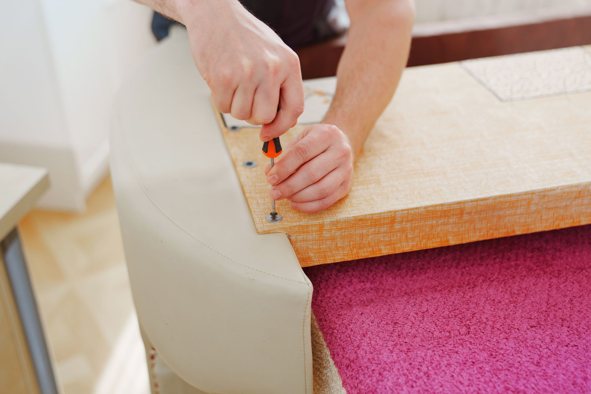A person is fixing a couch with a screwdriver.