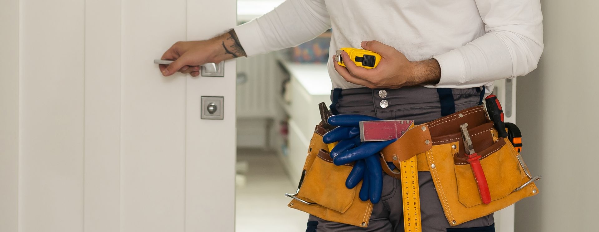 A man is standing in front of a door holding a tape measure.