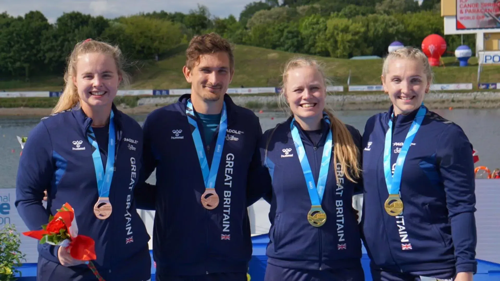 Four rowers from Great Britain, two women and one man, wearing medals and standing outdoors.