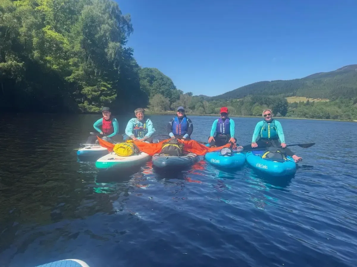 A group of people are sitting in kayaks on a lake.