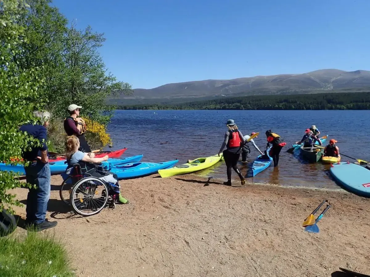 A group of people are getting ready to go kayaking on a lake.